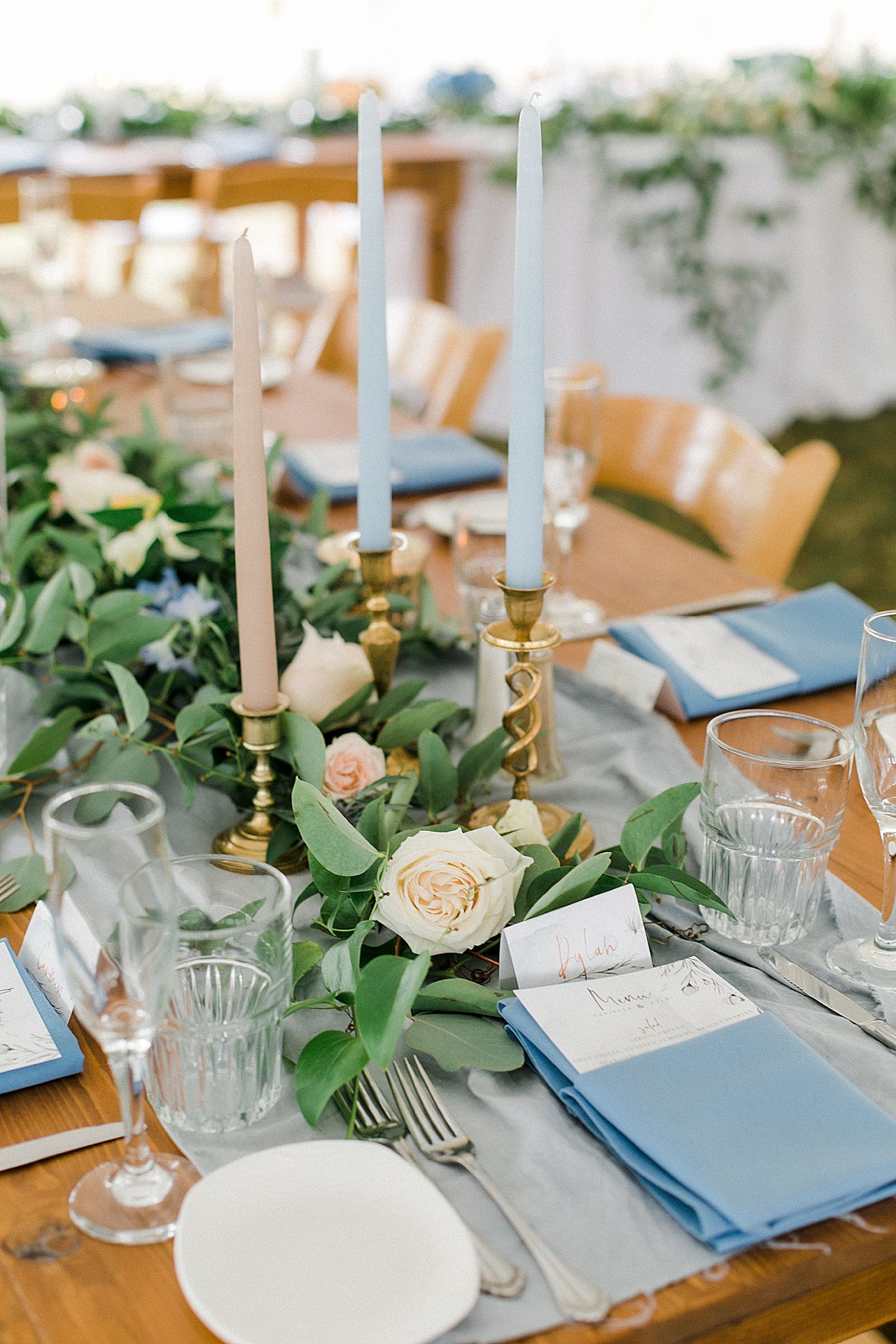 Wedding reception center pieces with flowers, candles and a light blue runner in Elberta, Michigan