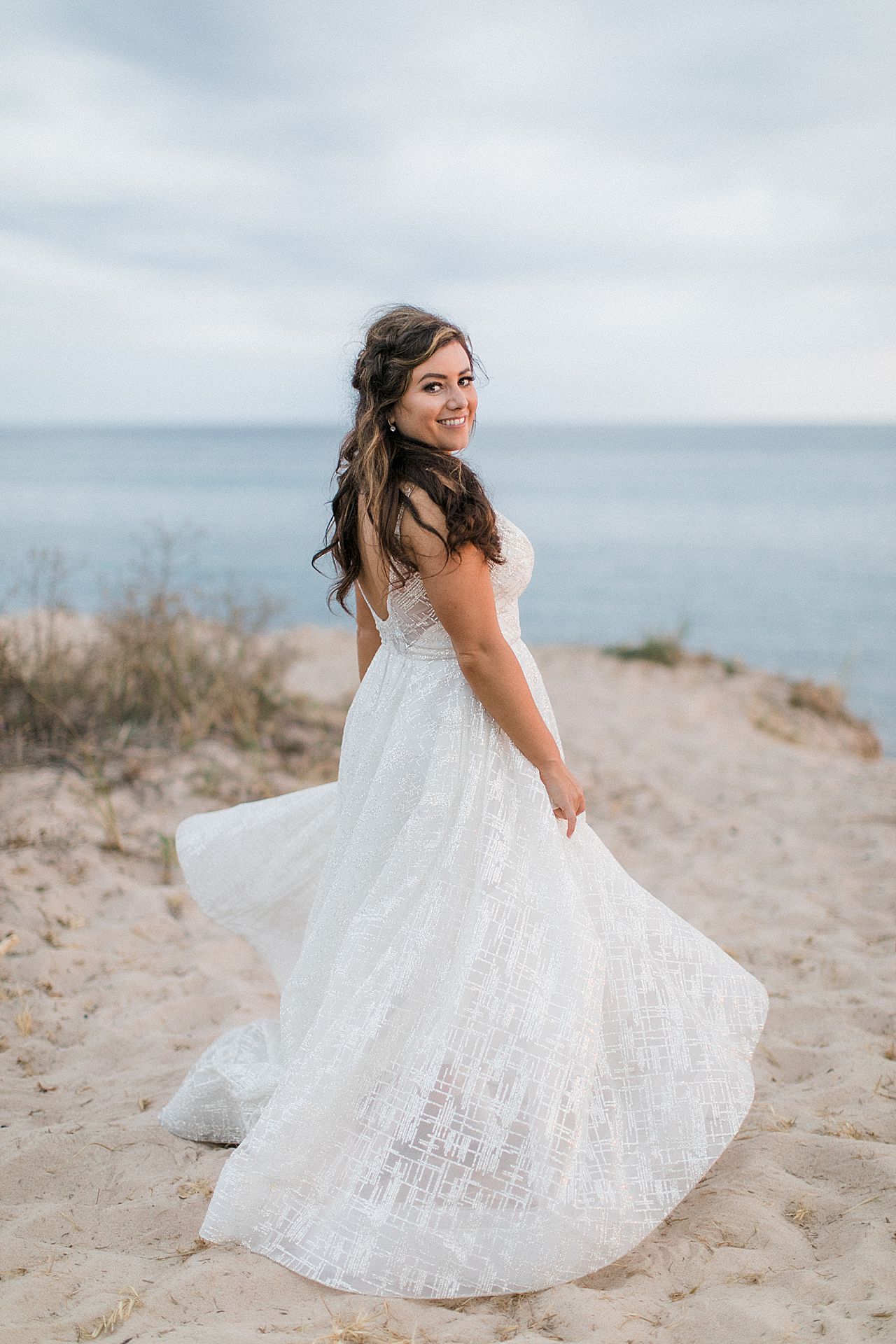 A bride twirling her dress on the beach along Lake Michigan at sunset in Northern Michigan