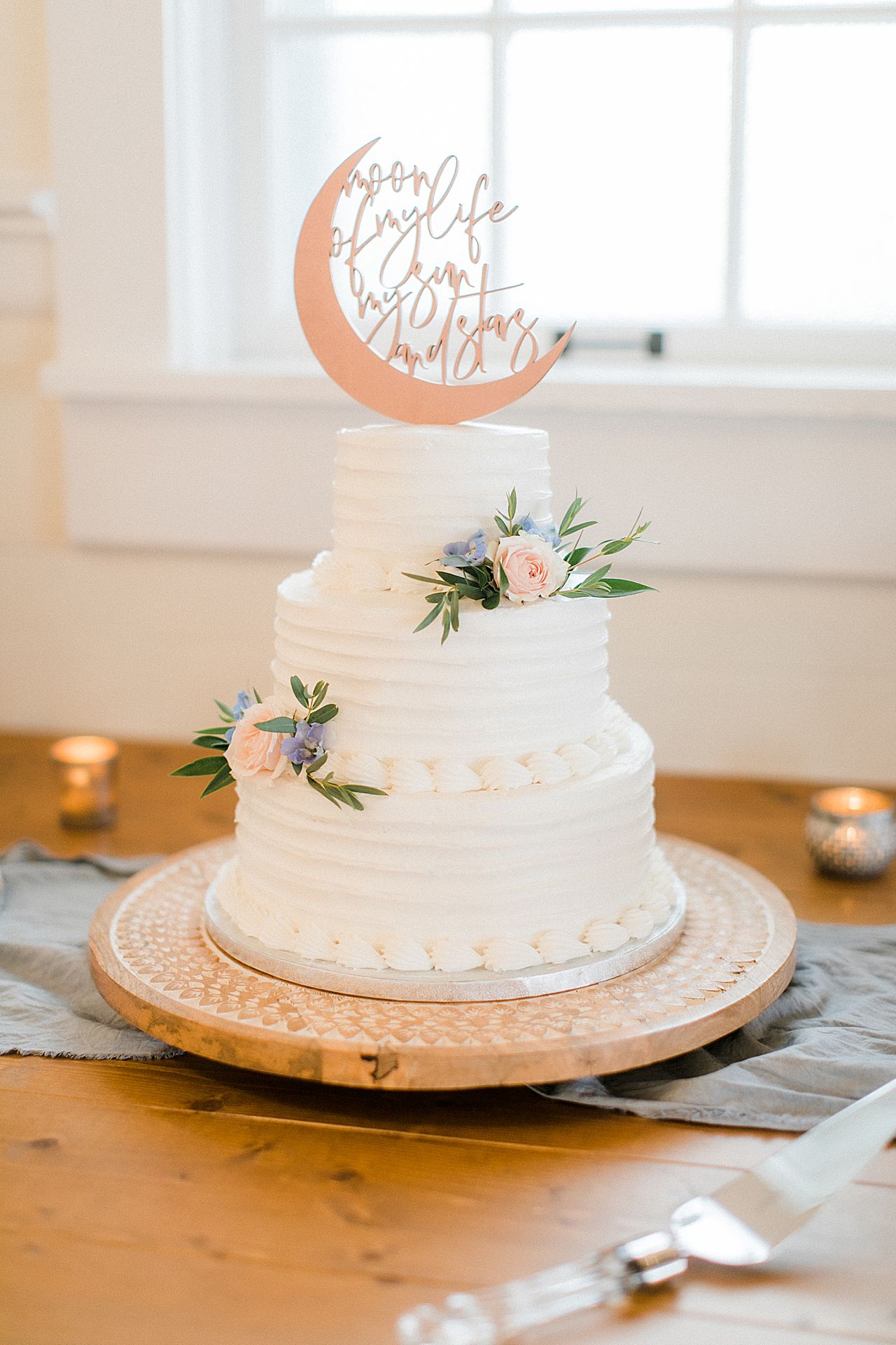 A 3 tier white wedding cake with pink and blue flowers at the Elberta Life Saving Station