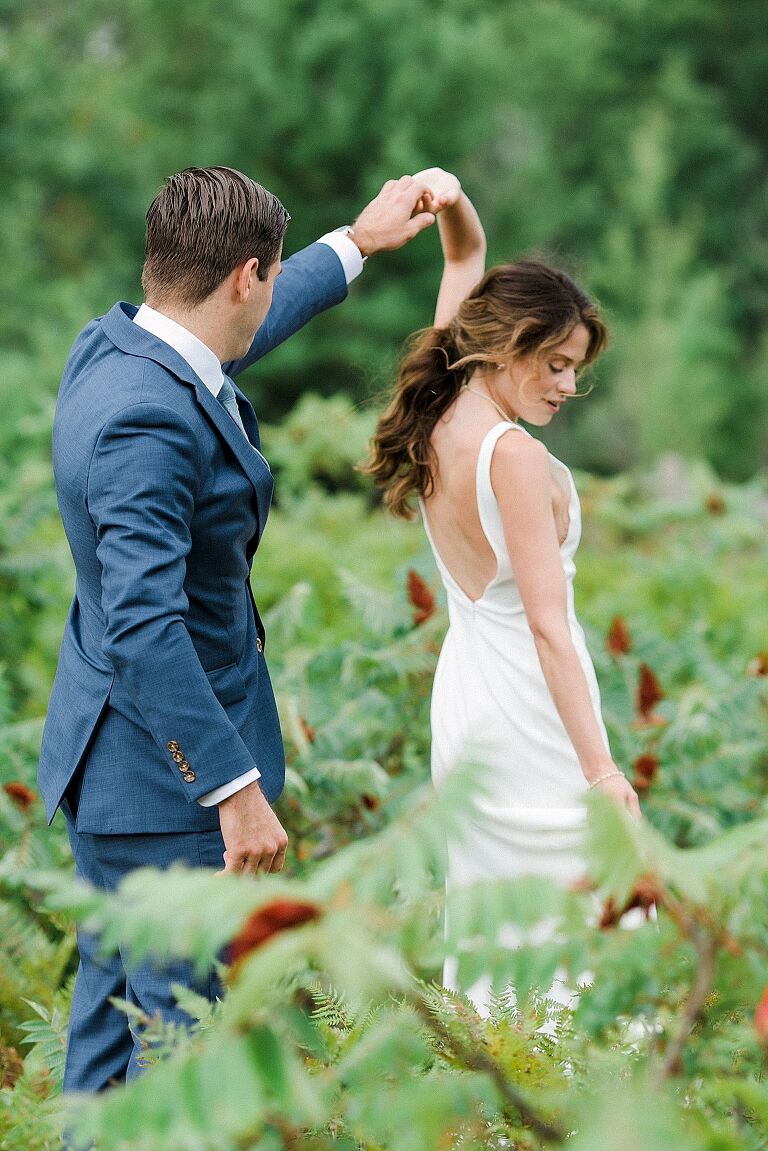 A groom twirling his bride in a field at Houdek Dunes Natural Area in Leland, Michigan