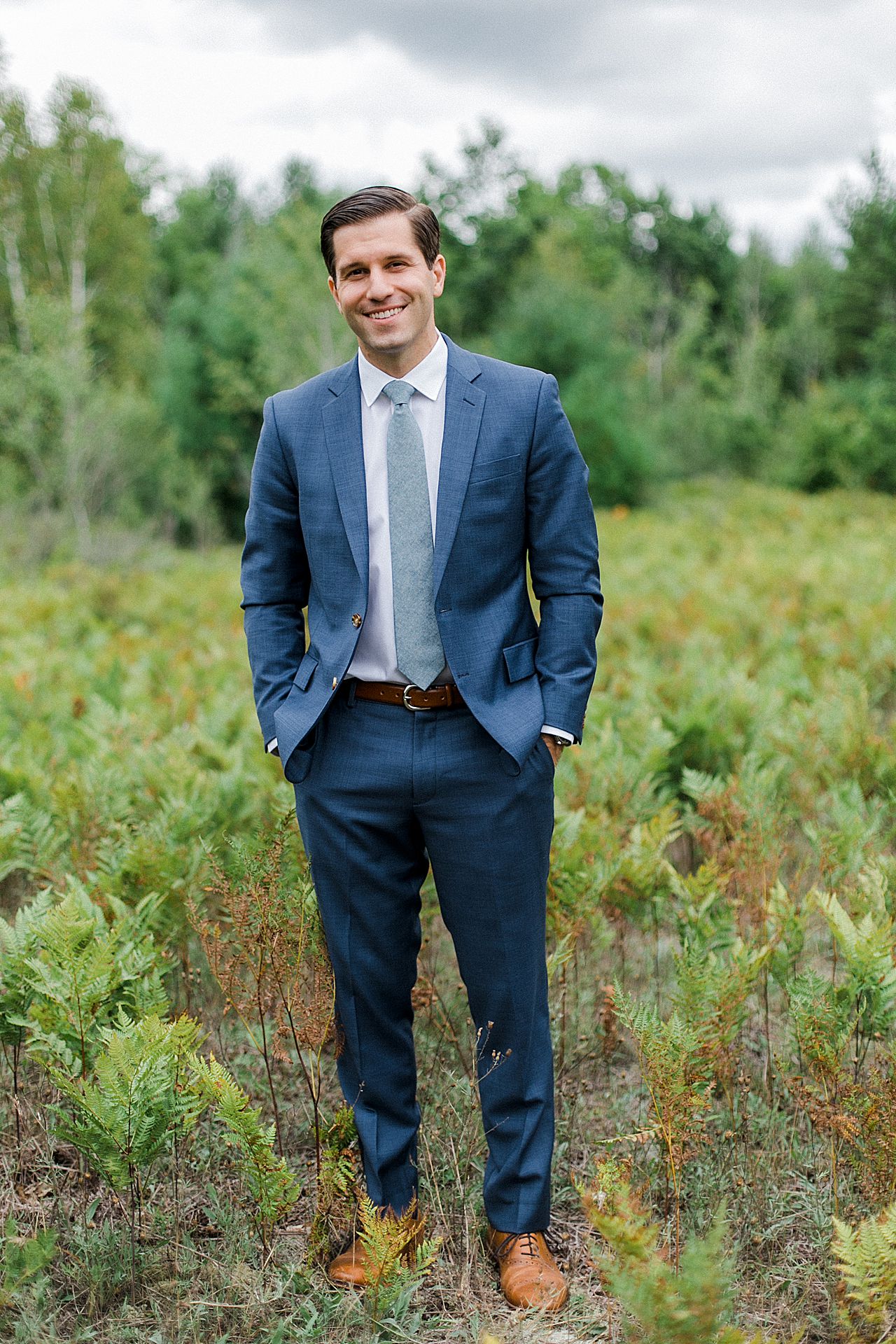 Groom portraits in a field full of ferns in Leland, Michigan