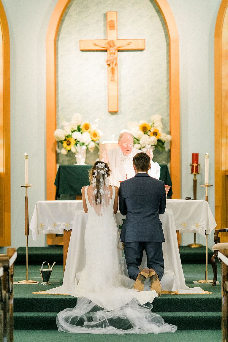 A bride and groom kneeling at the alter at their wedding ceremony in Suttons Bay, Michigan