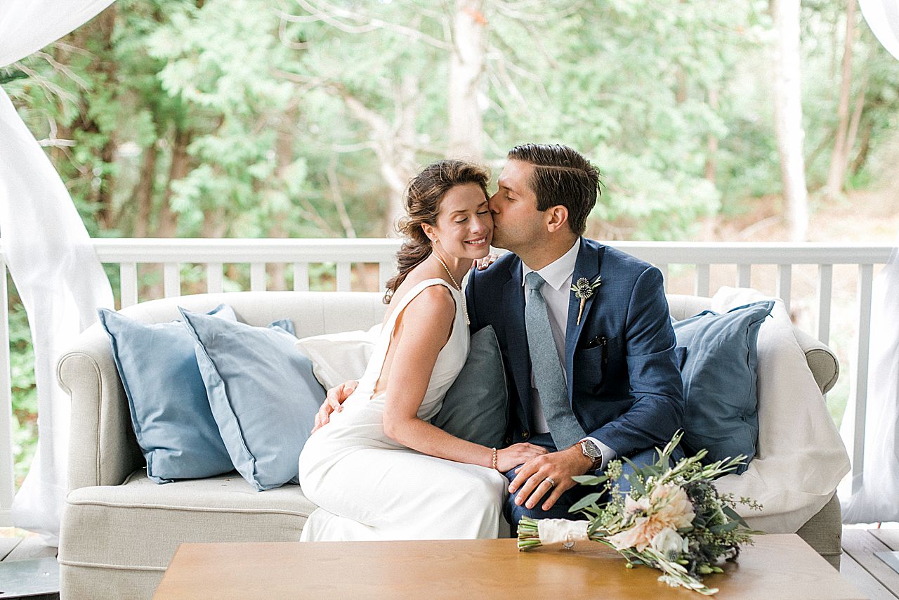 A groom kissing the bride's cheek on a porch in Northport, Michigan
