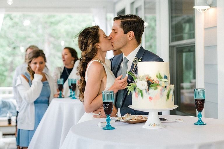A bride and groom kissing after cutting their wedding cake in Northport, Michigan