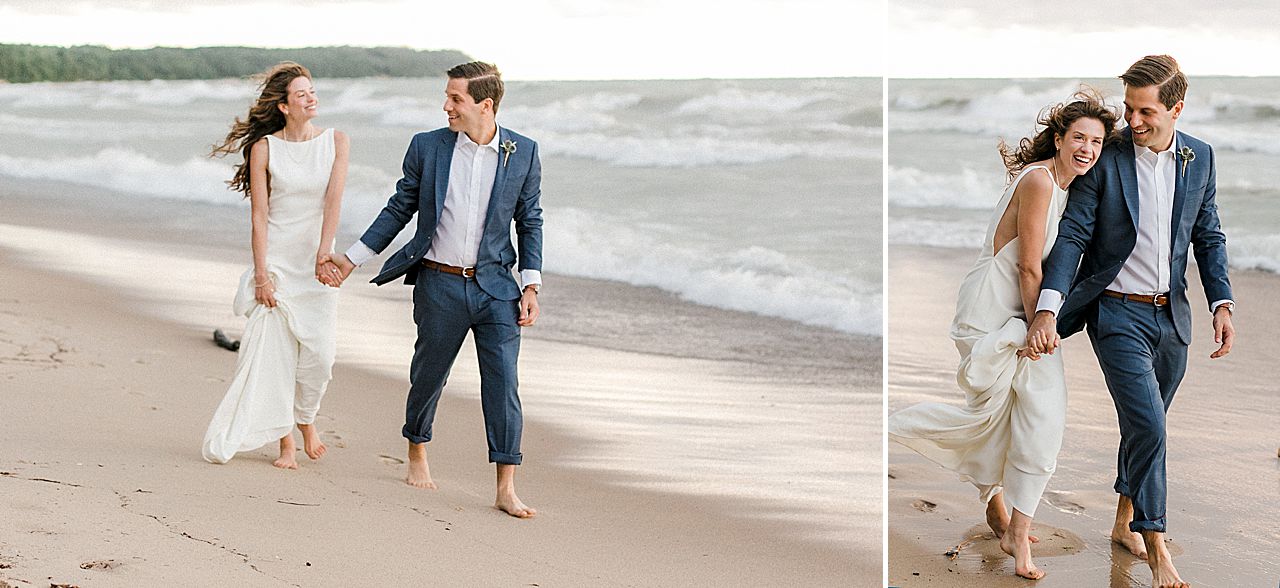 A bride and groom laughing while walking down the lakeshore in Northport, Michigan
