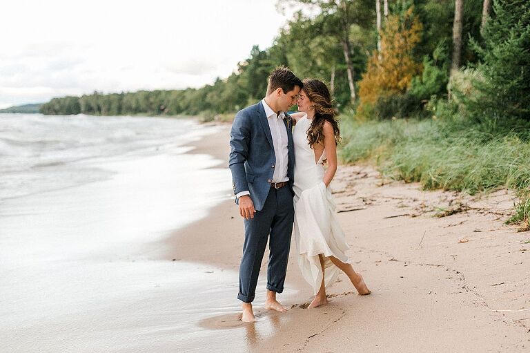 A bride and groom touching foreheads with their eyes closed by Lake Michigan