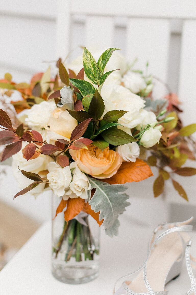 A bridal bouquet with white, cream, and orange flowers in Charlevoix, Michigan