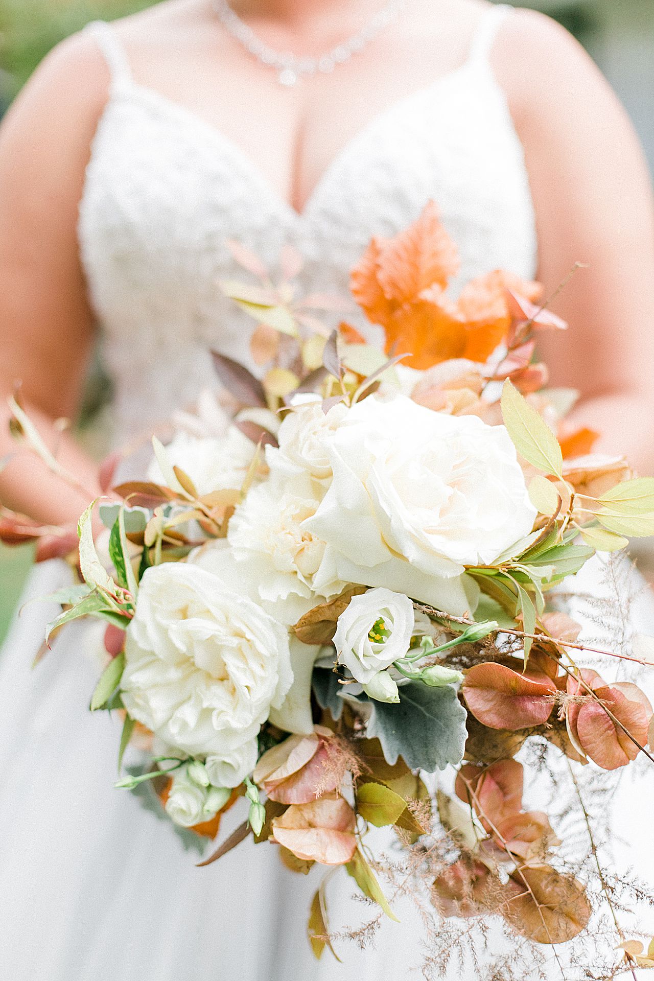 A bridal bouquet with white, cream, and orange flowers in Charlevoix, Michigan