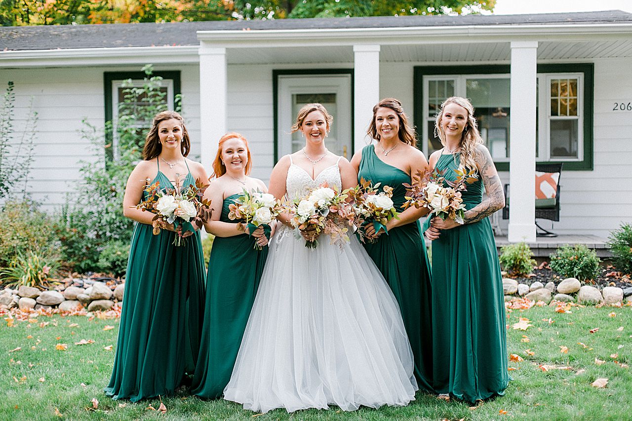 A bride with her 4 bridesmaids who are wearing dark green dresses in Charlevoix, Michigan