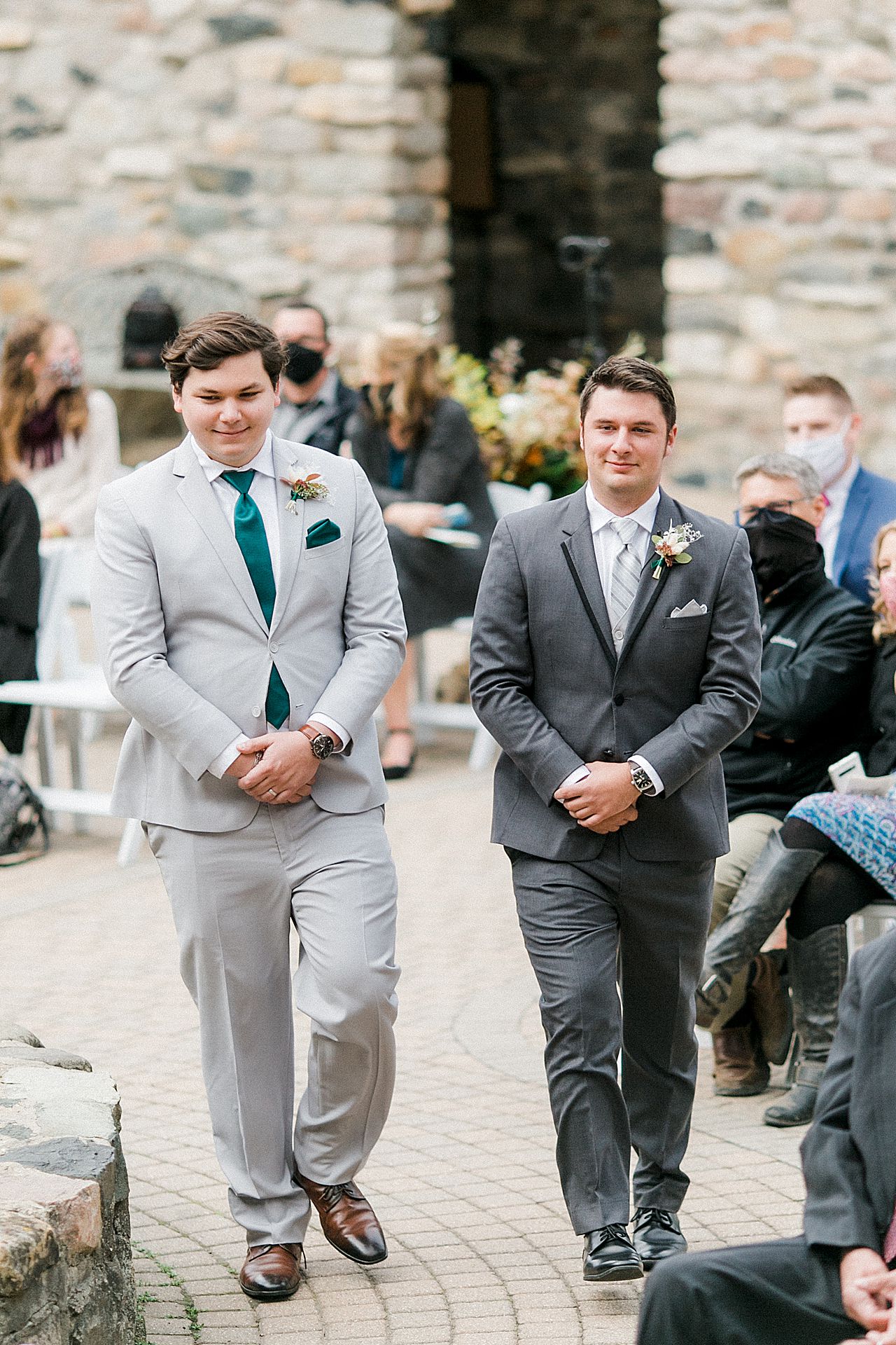 The groom and his best man walking down the ceremony aisle in the Queens Courtyard in Charlevoix, Michigan