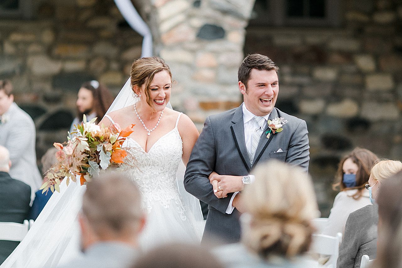 A bride and groom holding hands as they walk down the aisle after their wedding ceremony at Castle Farms