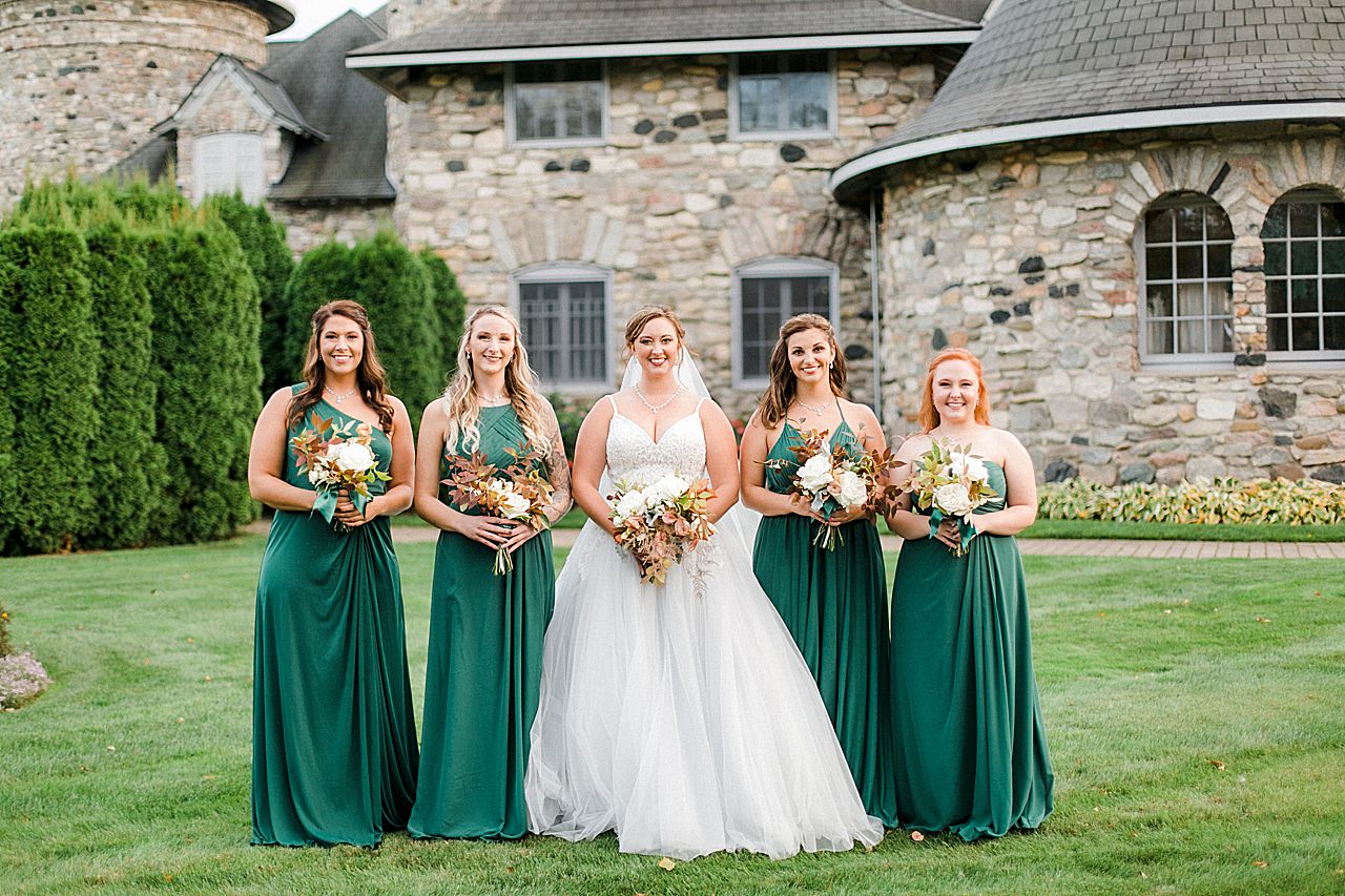 A bride with her 4 bridesmaids who are wearing dark green dresses in Charlevoix, Michigan at Castle Farms