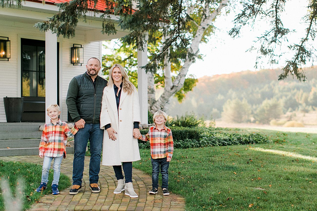 Family portrait of a mother, father, and their 2 boys in front of their farmhouse home in Northern Michigan