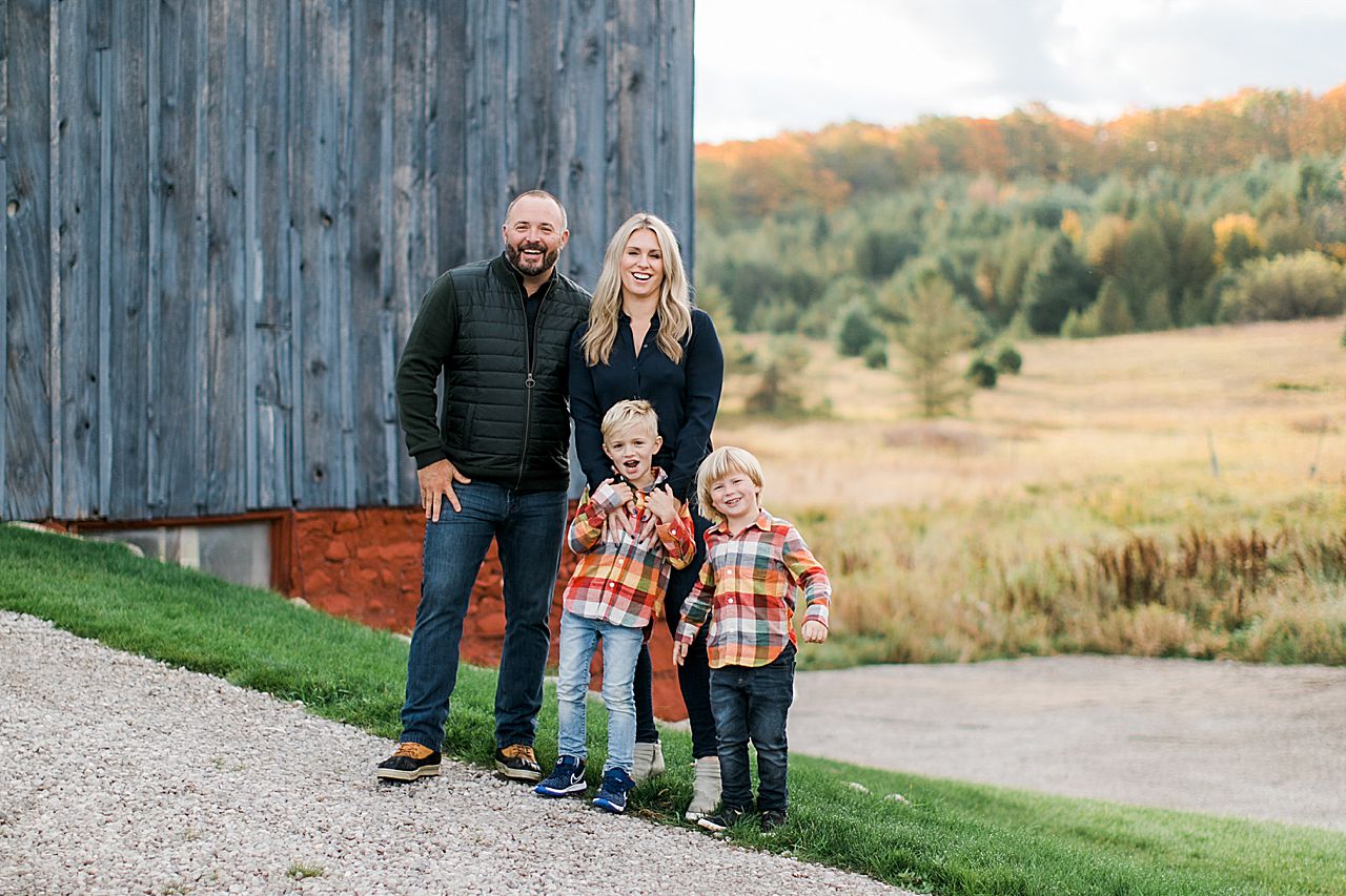 A family of 4 in front of a barn in the fall in Petoskey, Michigan