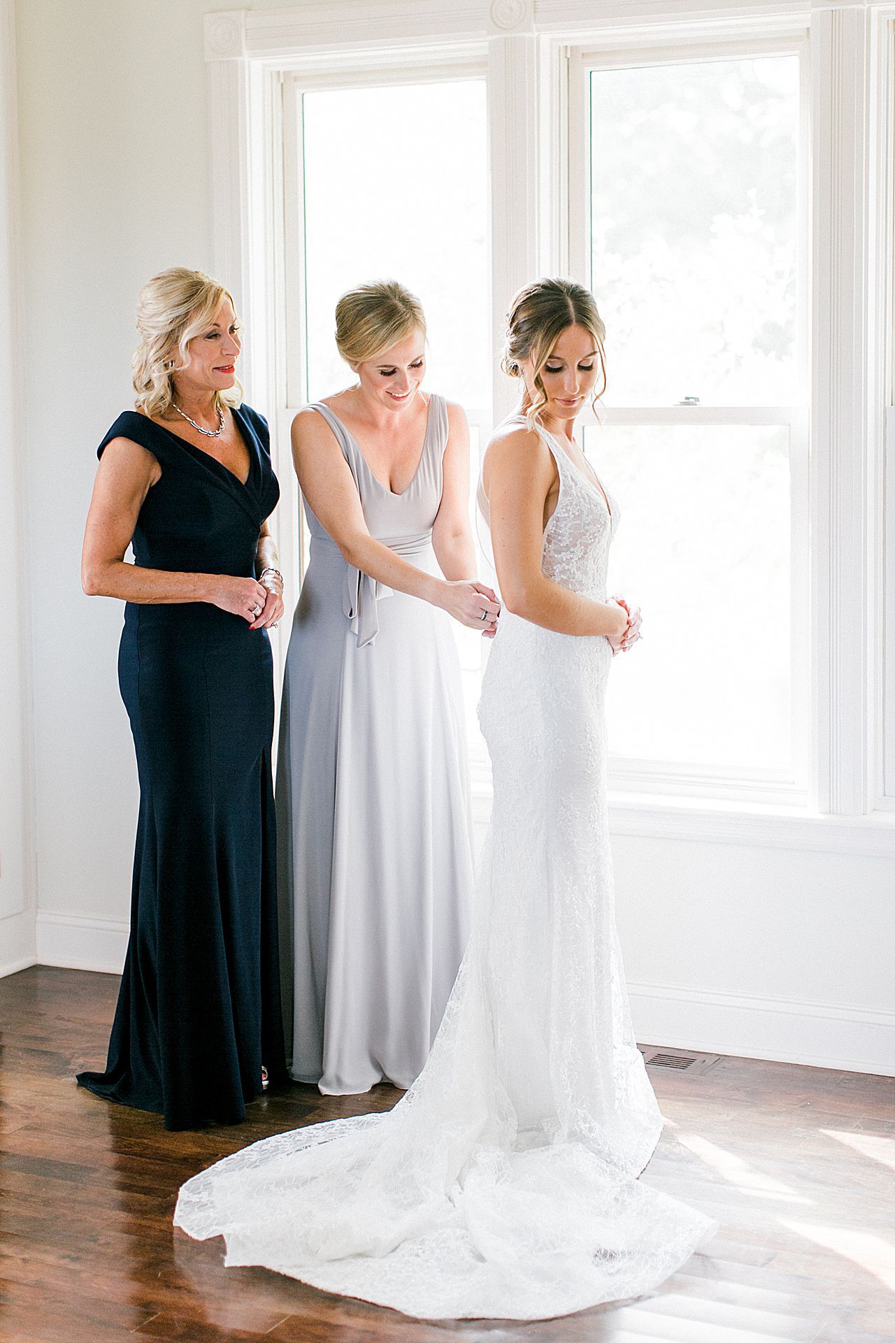 A bride putting on her wedding dress with her mother and sister at Aurora cellars in Michigan