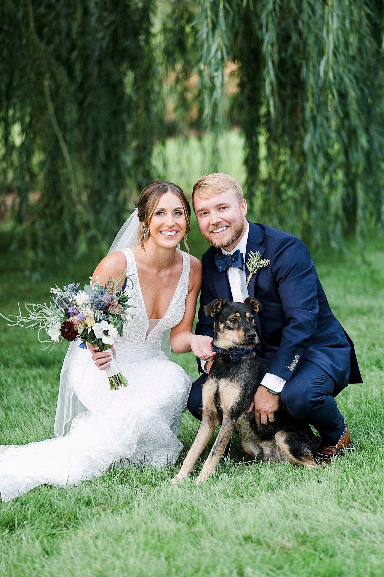 A bride and groom taking a portrait with their dog