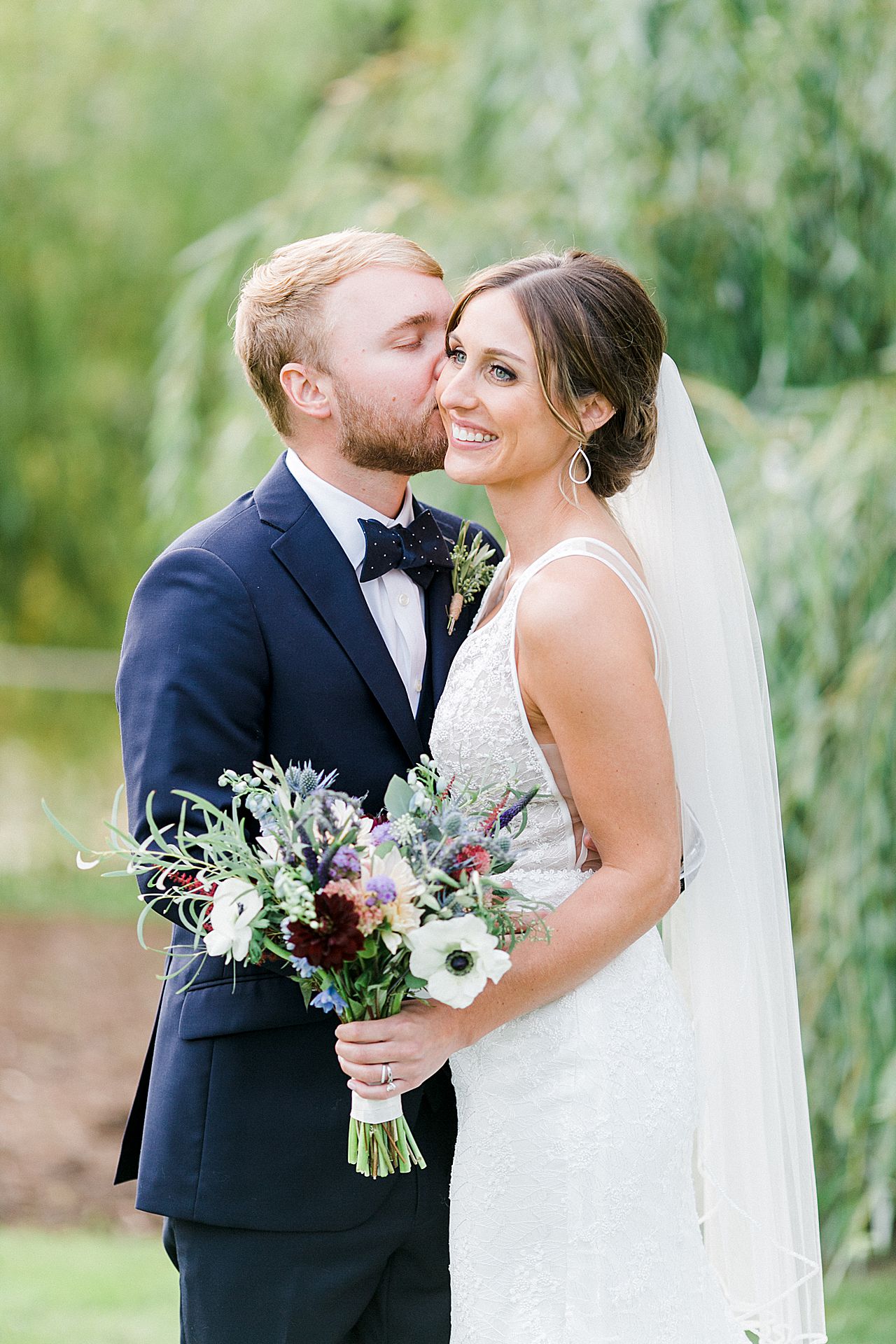 A groom kissing his brides cheek