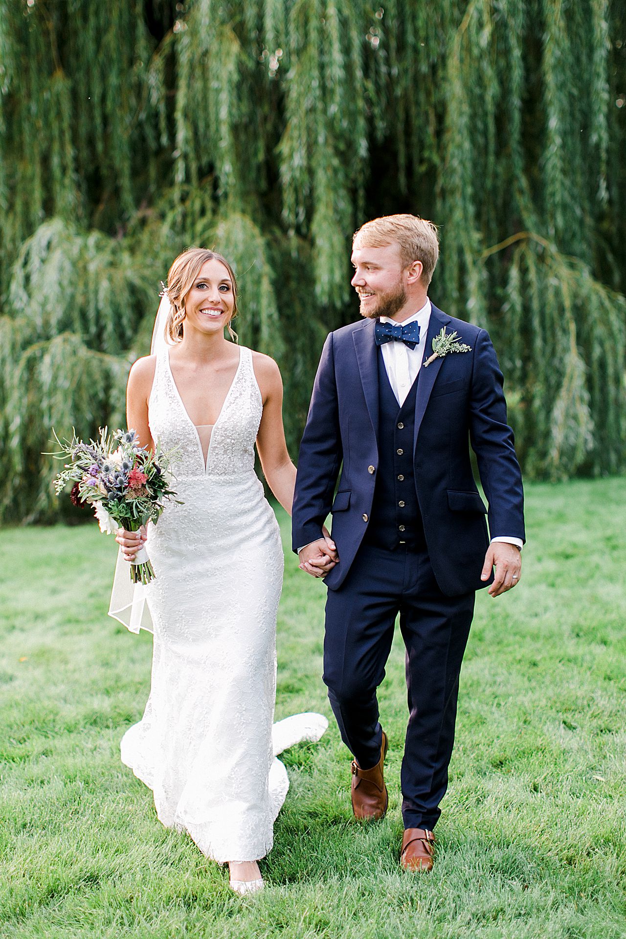 A bride and groom holding hands and walking at Aurora cellars in Michigan