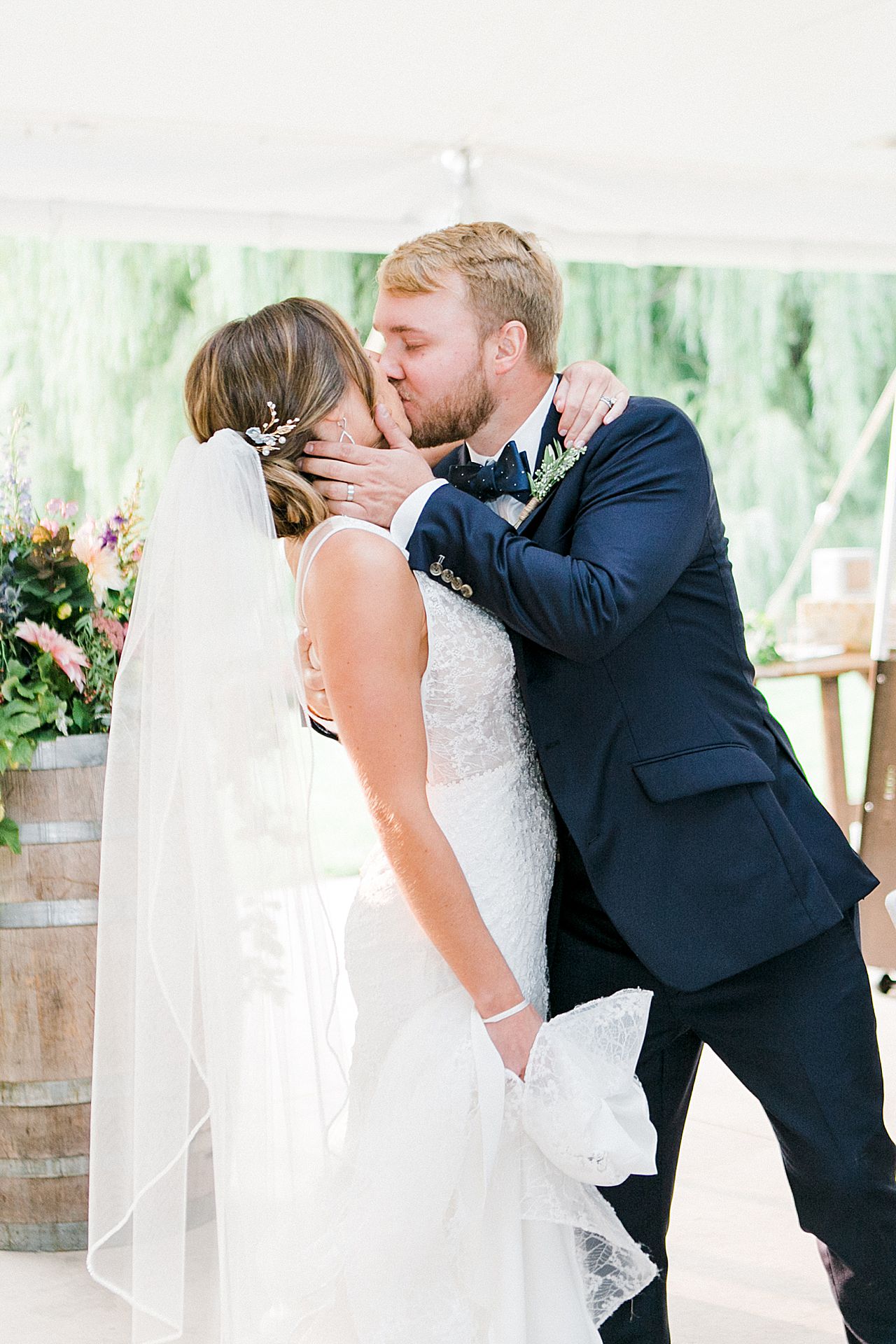 A bride and groom walking into their wedding reception and kissing