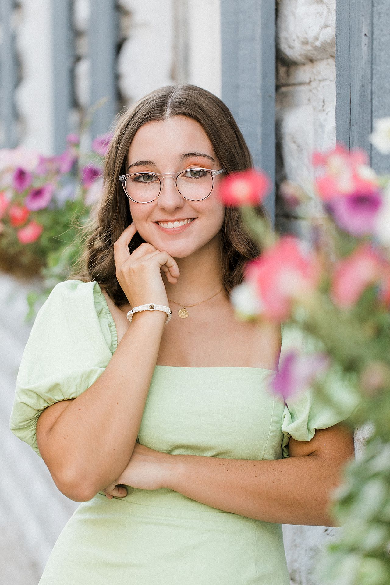 A senior portrait session with a girl leaning up against a building in downtown Charlevoix
