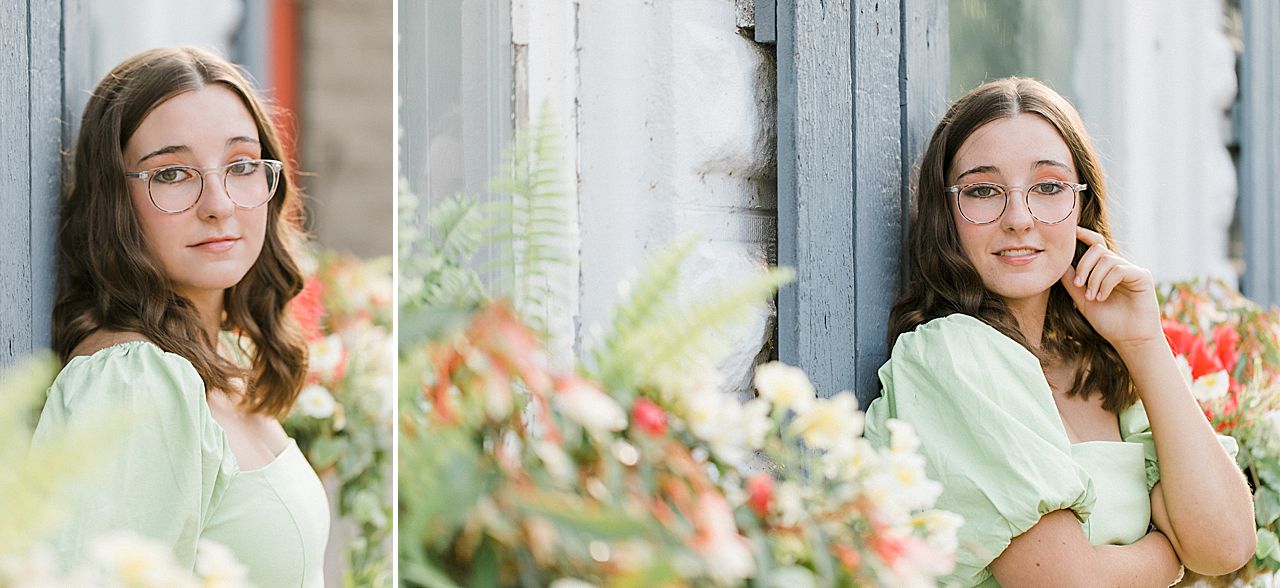 A girl smiling in a green dress and glasses during her senior portrait session in Charlevoix, MI