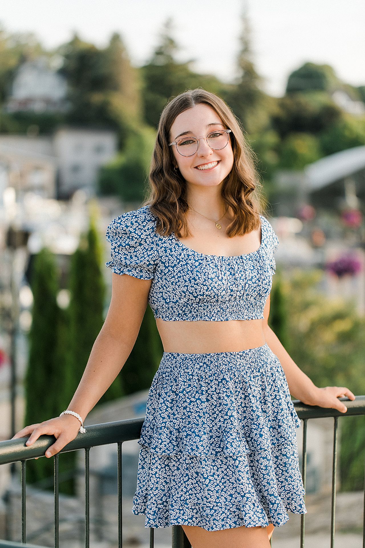 A girl wearing a blue crop top at a marina in Michigan during her senior portrait session