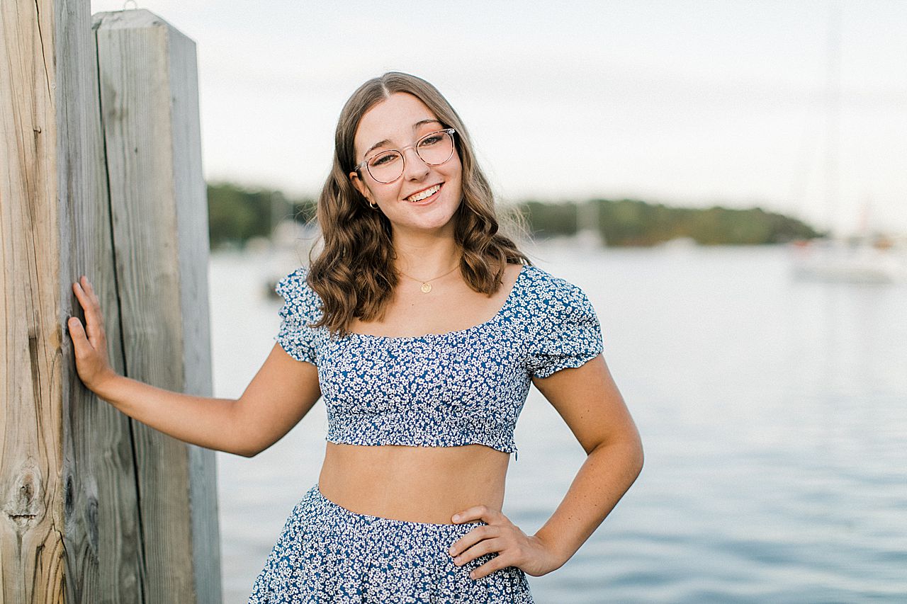 A girl on a dock in the summer in Michigan during her senior portrait session