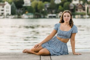 A girl on a dock in the summer during her senior portrait session in Charlevoix