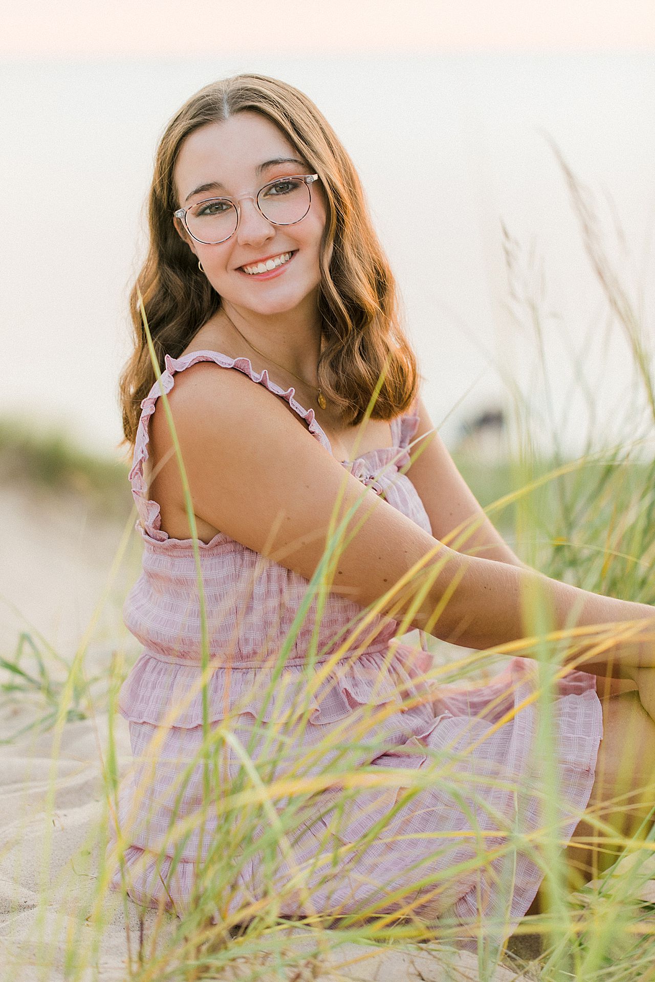 A senior portrait session with a girl in a pink dress on sand dunes in Northern Michigan