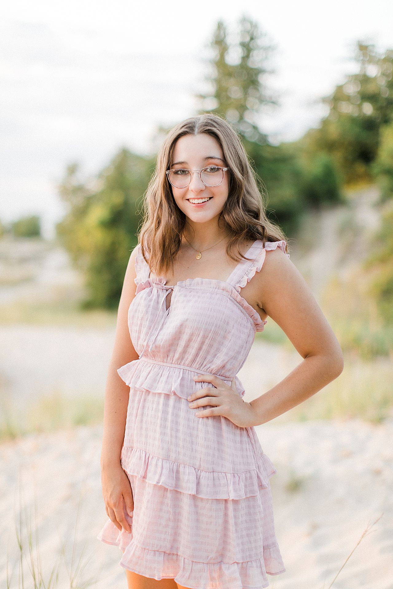 A senior portrait session with a girl in a pink dress on sand dunes in the summer in Northern Michigan