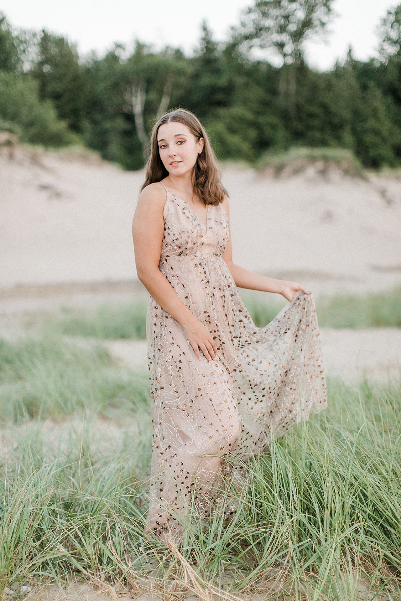 A girl's senior portrait session in sand dunes and beach grass in Michigan