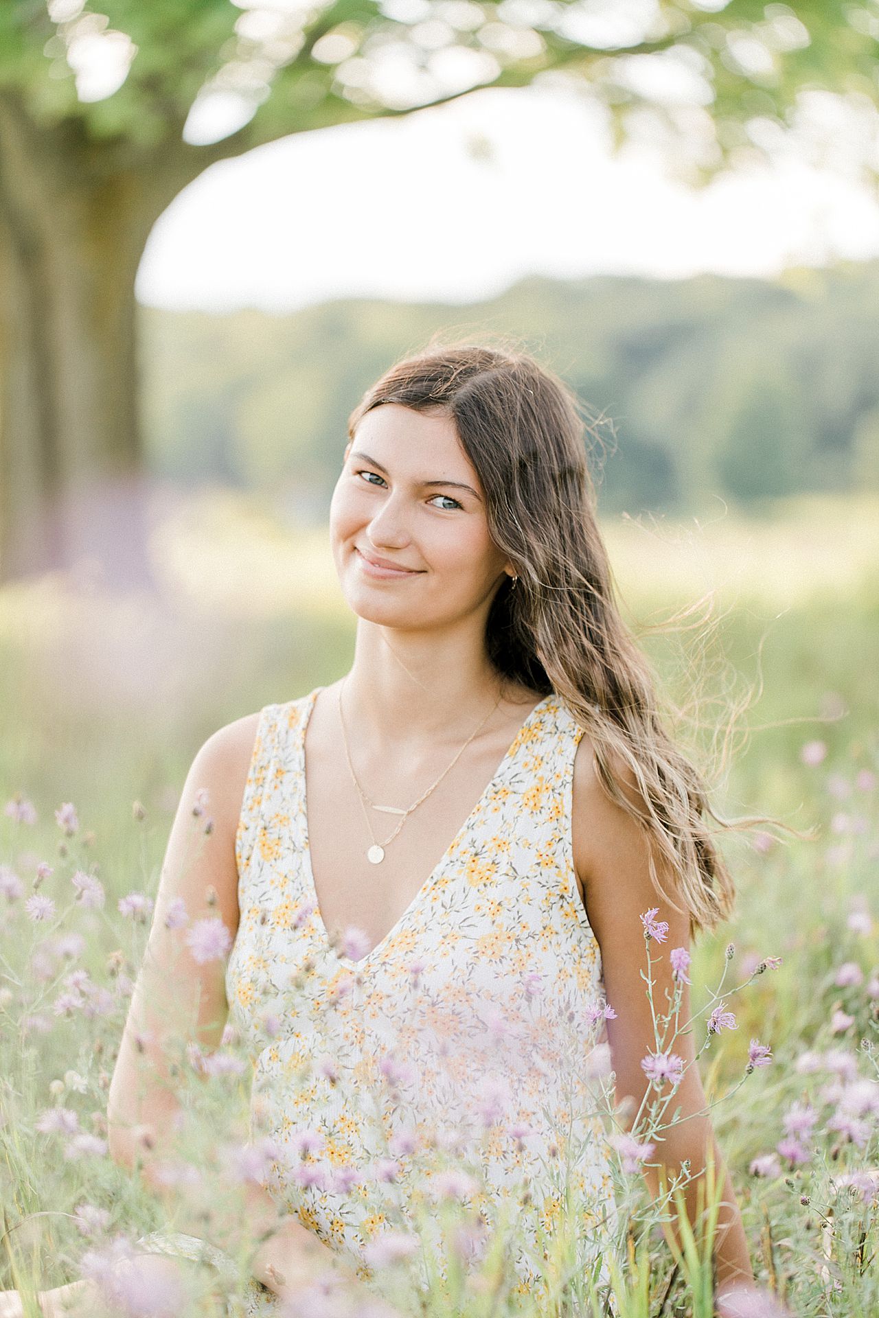 A girl sitting in a field in Leelanau Peninsula Michigan during her senior portrait photography session