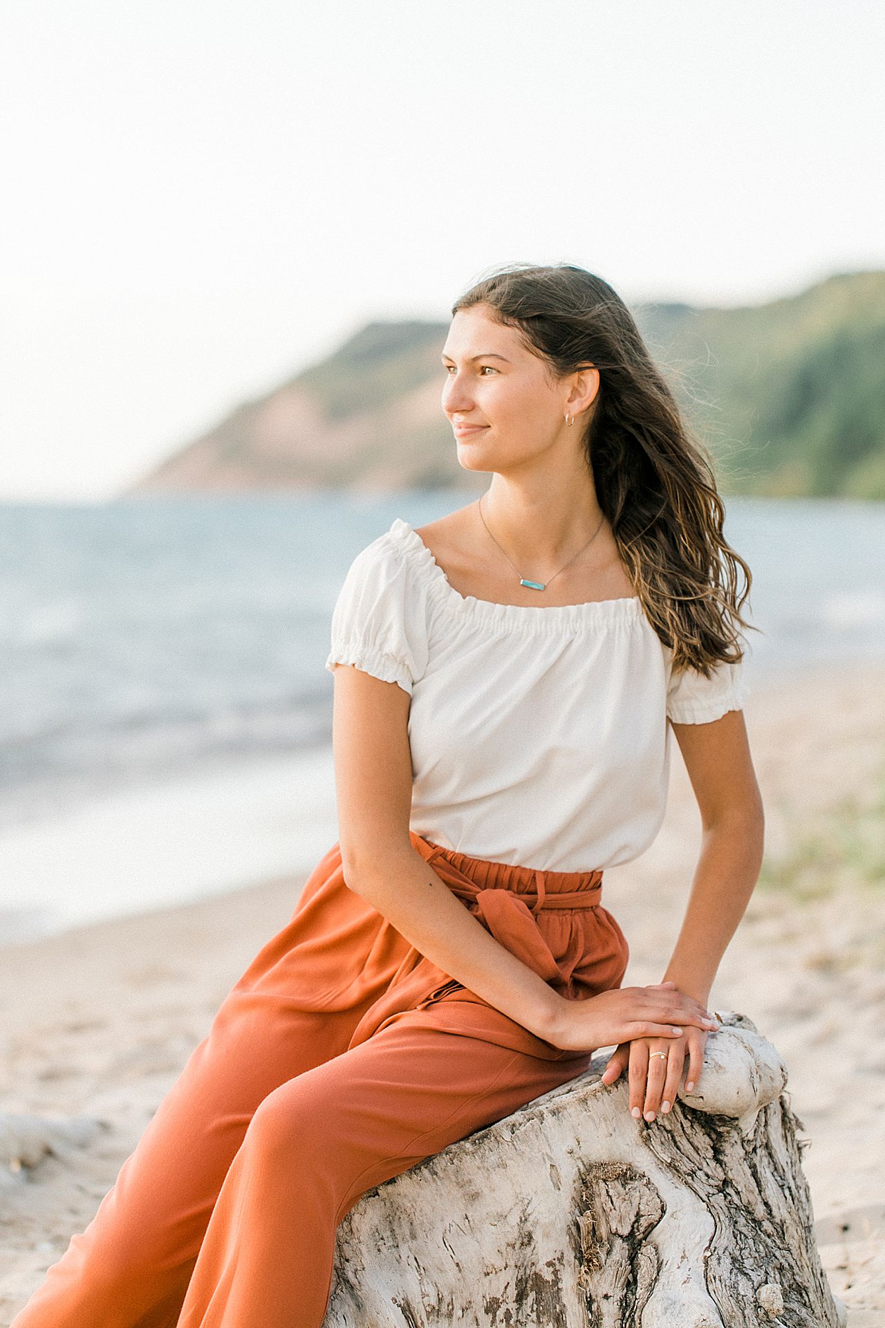 A girl sitting on a stump near the lake at Sleeping Bear Dune National Lakeshore