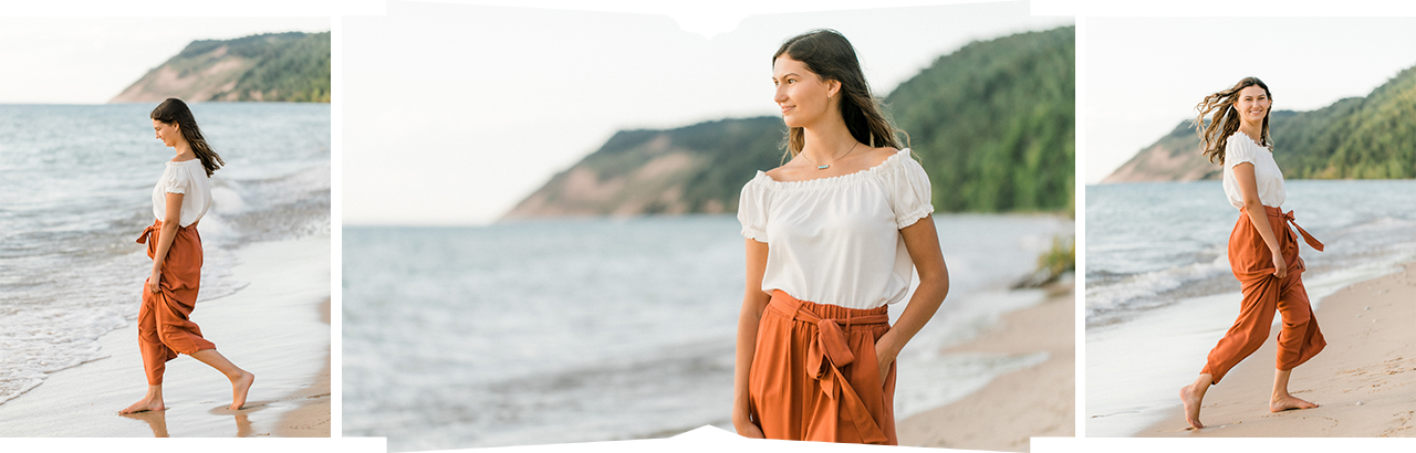 A girl running on the beach with a white top and orange wide leg pants in Empire, Michigan