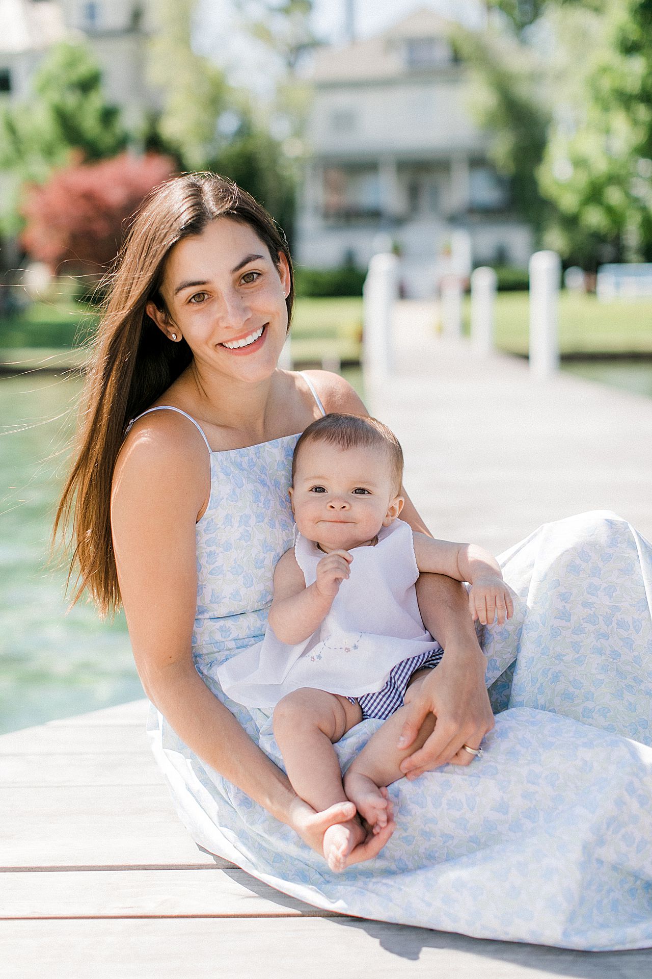 A baby girl with her mother sitting on a dock in Harbor Point