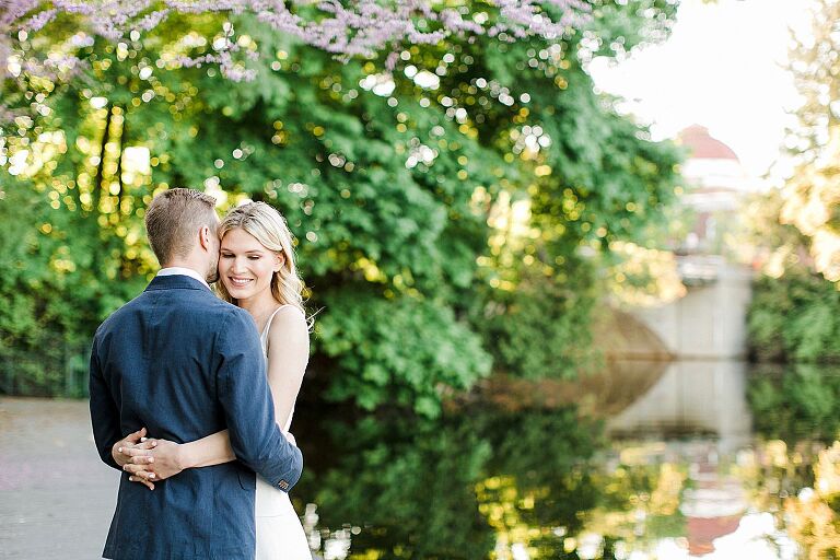 A couple taking engagement photos by the Boardman River at sunset in Traverse City, Michigan