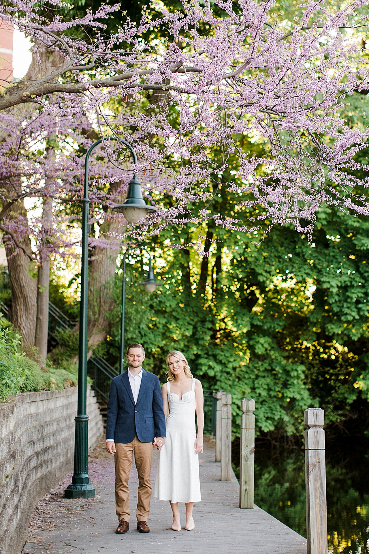 A couple on a boardwalk in Downtown Traverse City with a blooming purple tree overhead