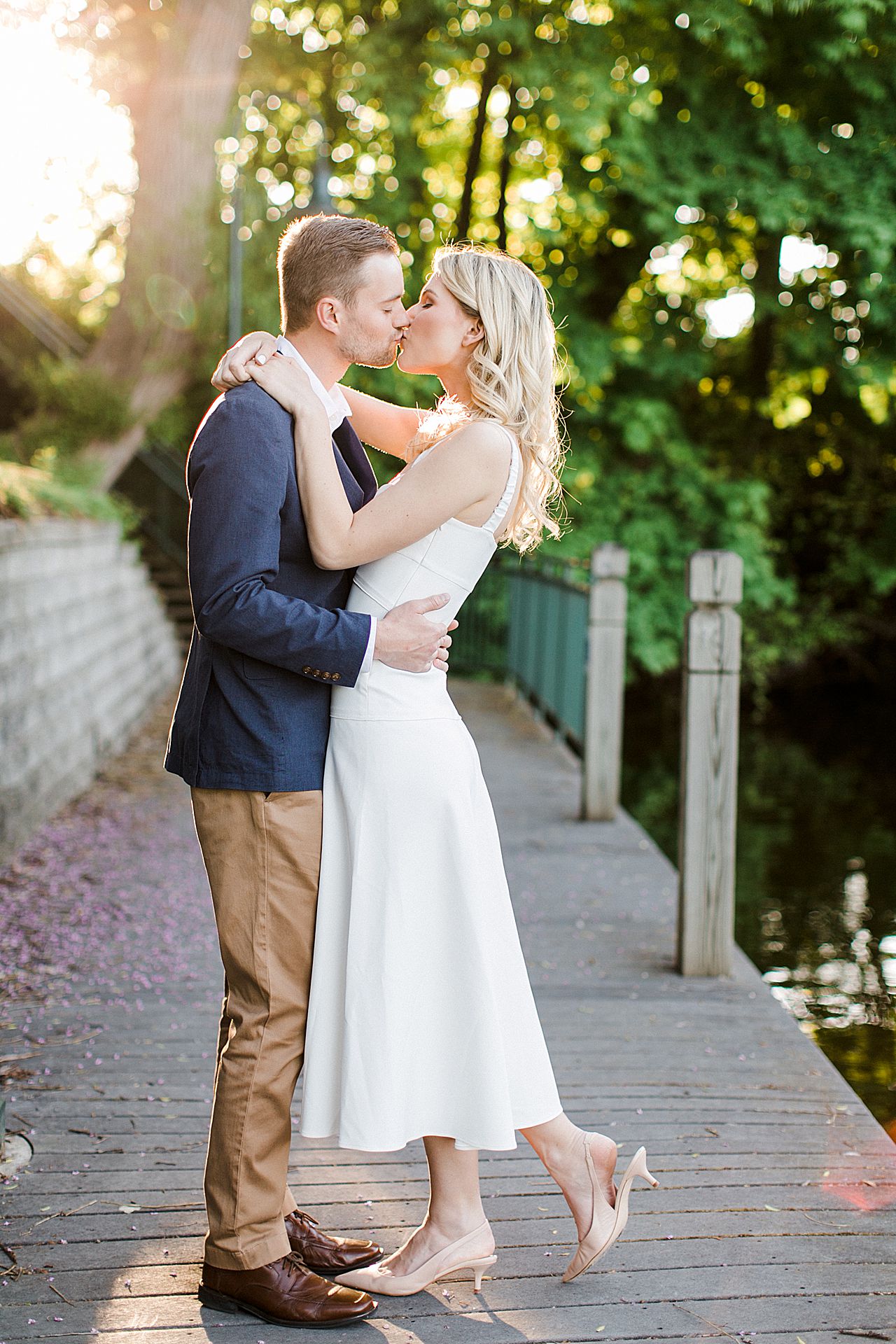 A couple on a boardwalk kissing with the sun shining behind them in Traverse City, Michigan