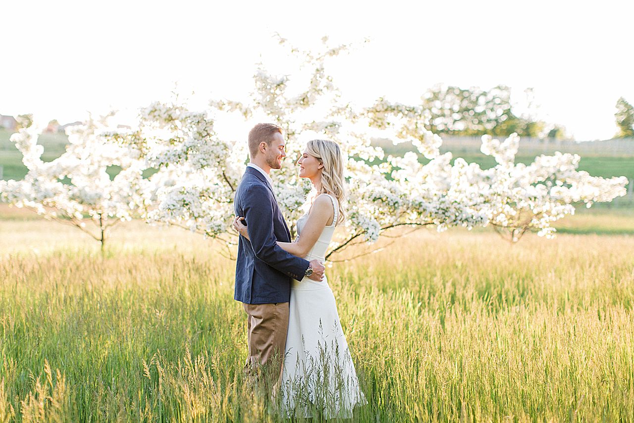 A couple taking photos by a blooming tree in the spring on Old Mission Peninsula in Michigan