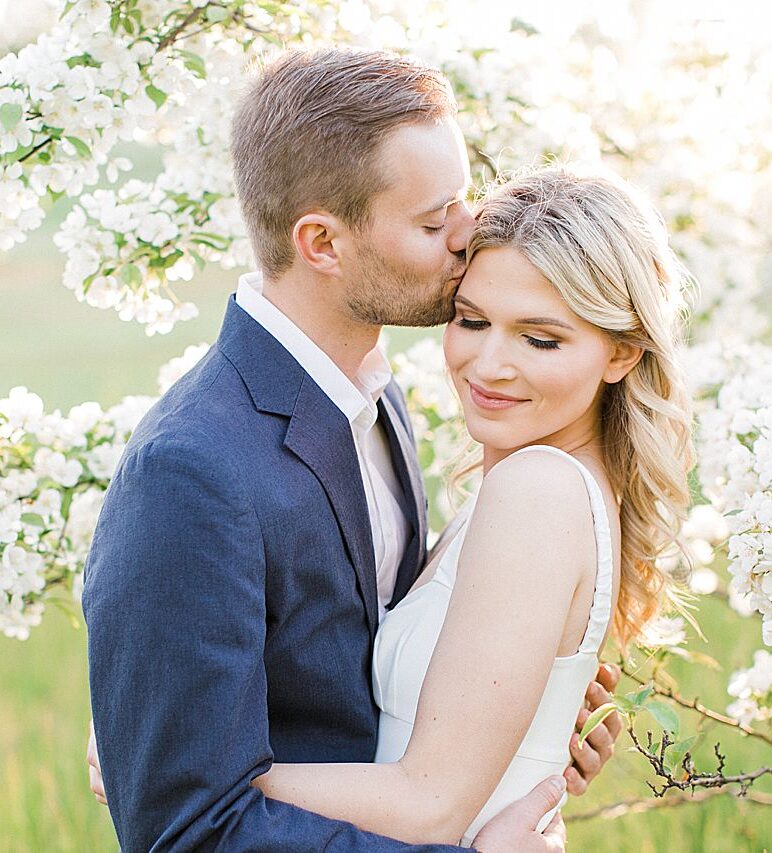 Engagement photos of a couple with a blooming tree in the background on Old Mission Peninsula