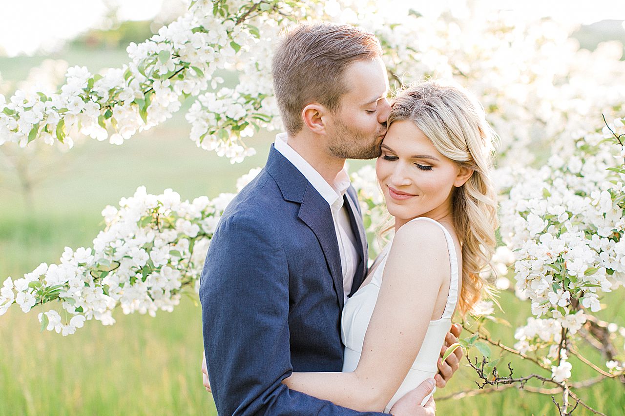 Engagement photos of a couple with a blooming tree in the background on Old Mission Peninsula