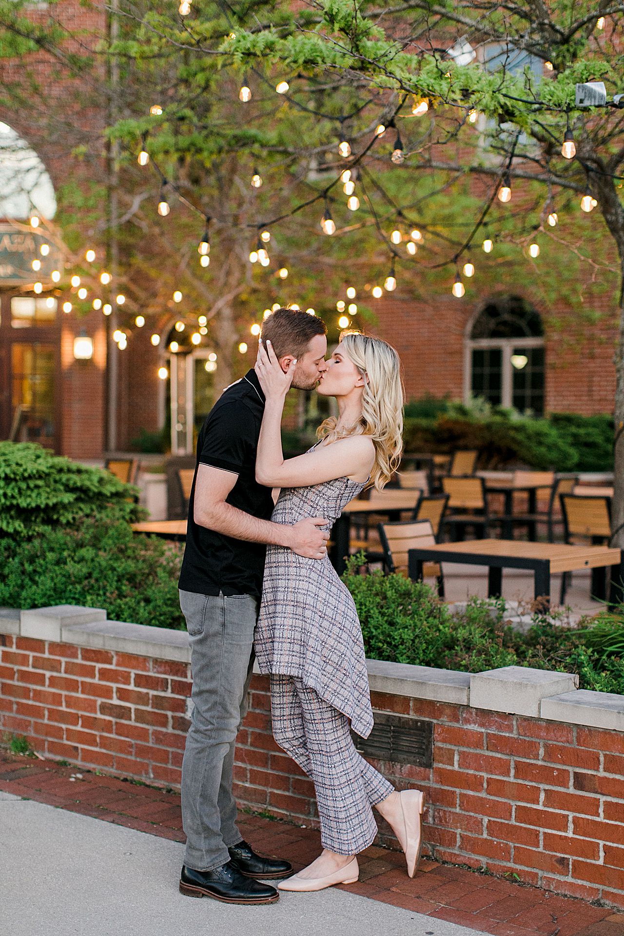 An engaged couple kissing in Downtown Traverse City at dusk