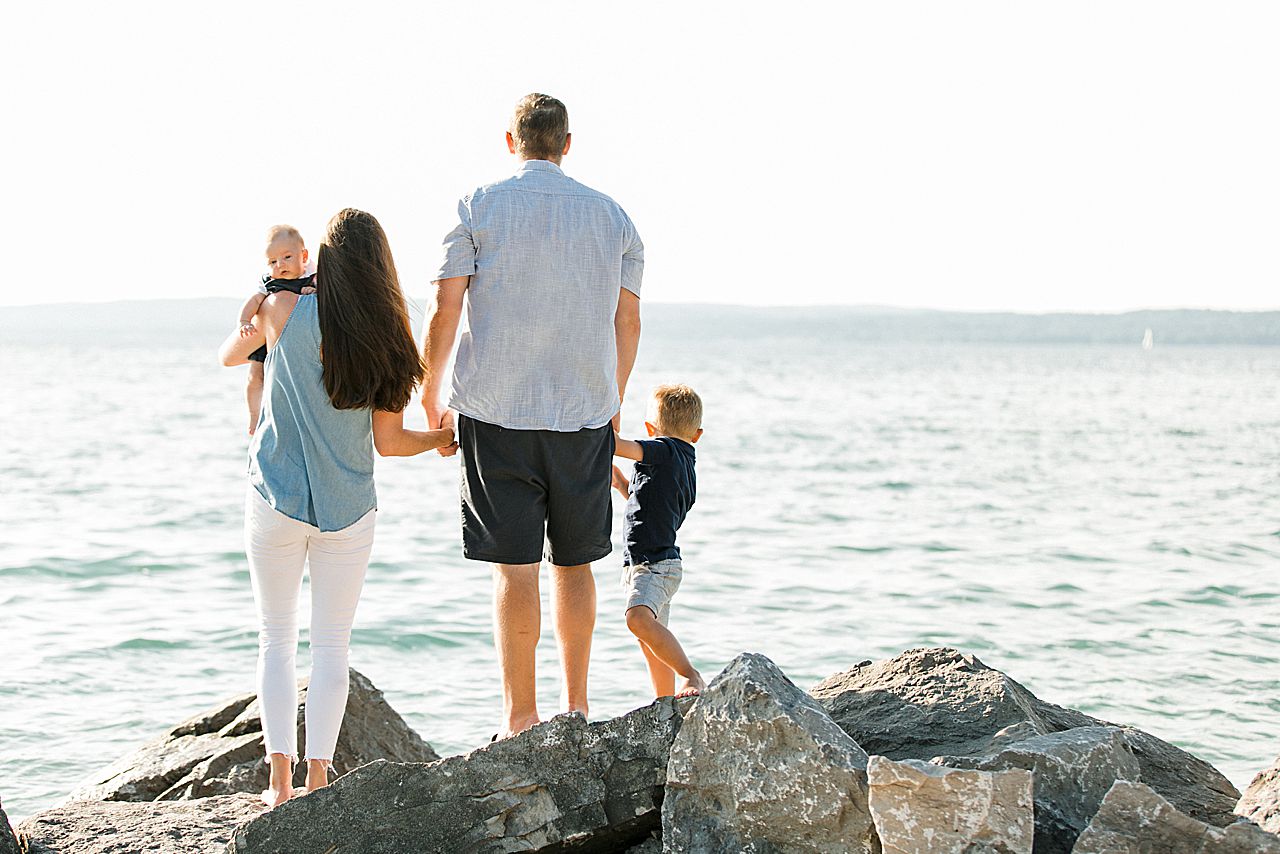 A portrait of a mother, father, and their 2 young sons in Petoskey, Michigan looking at Little Traverse Bay