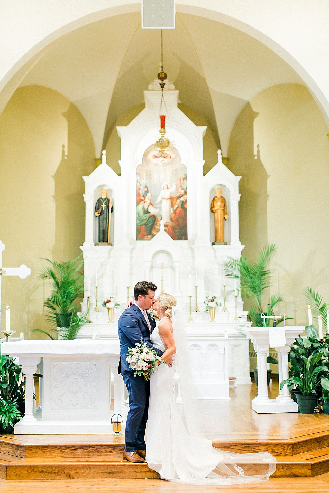 A bride and groom kissing at the altar at Holy Childhood of Jesus Catholic Church in Harbor Springs, Michigan