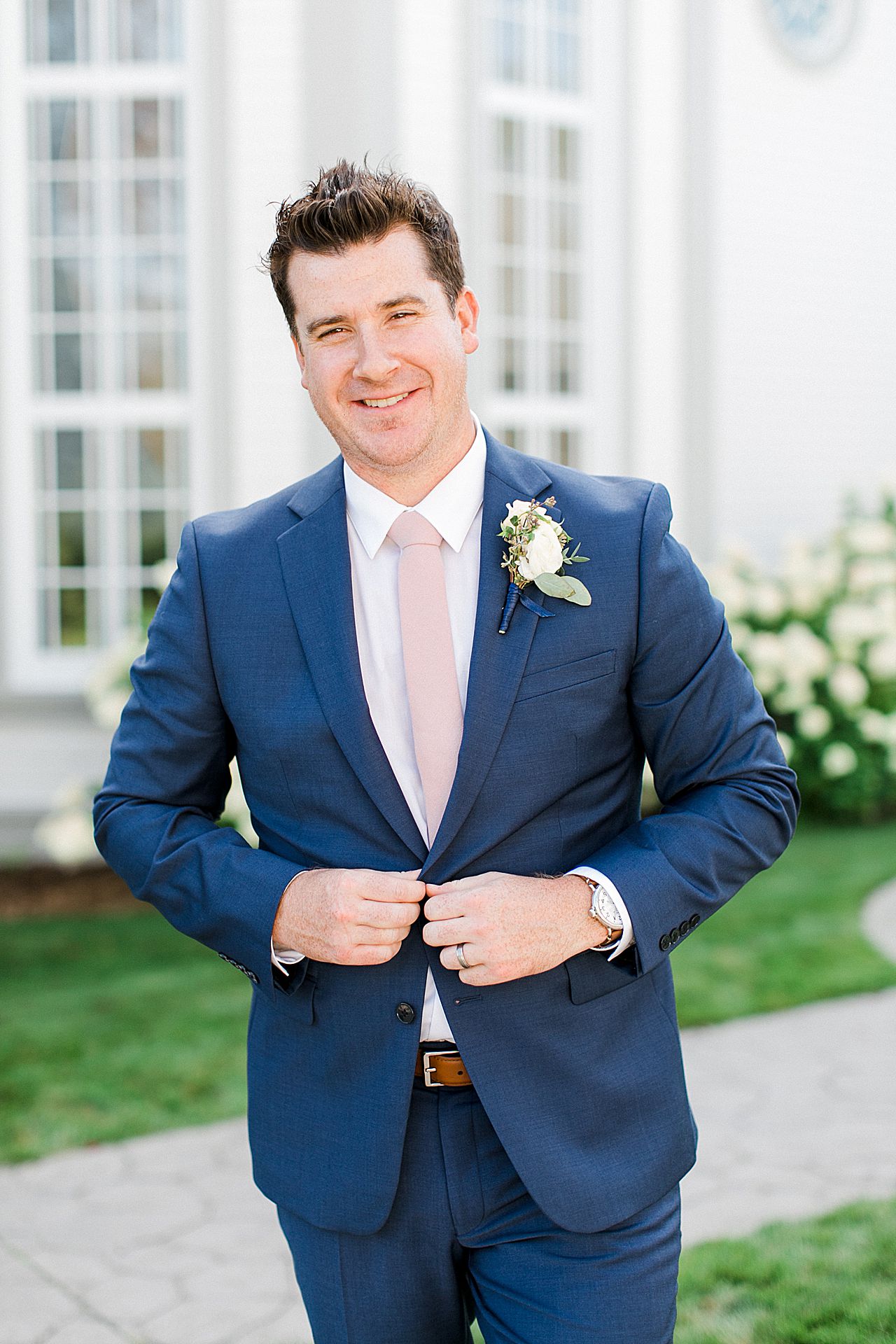 A groom walking in his blue suit during portraits in Harbor Springs, Michigan