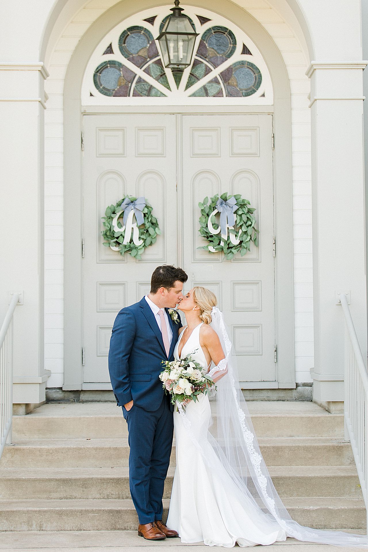 A bride and groom kissing in front of the Holy Childhood of Jesus Catholic Church in Harbor Springs, Michigan