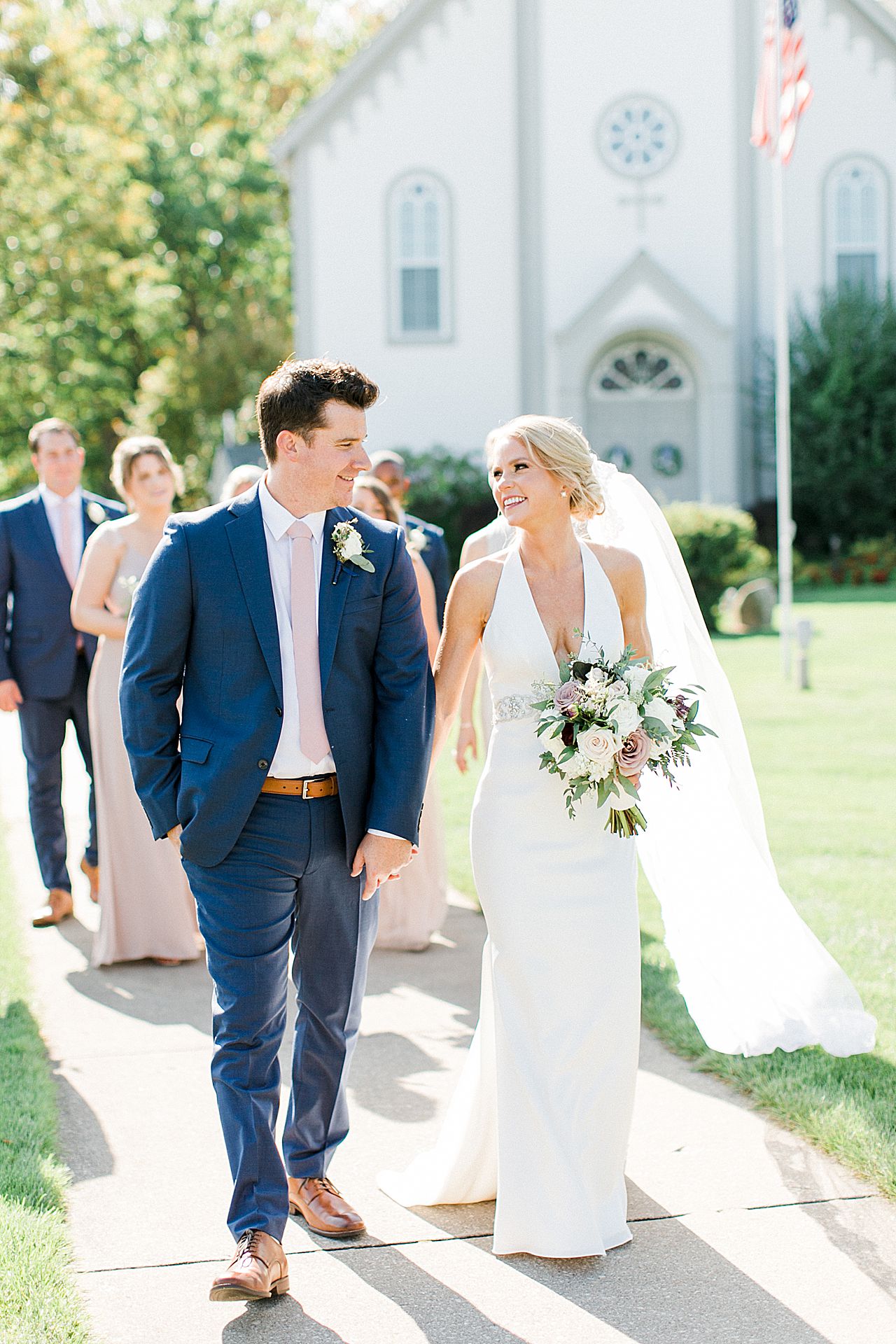 A bride and groom holding hands and walking in Harbor Springs, Michigan with their bridal party