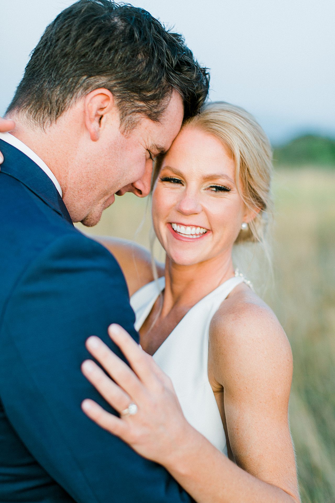 A bride laughing with her groom at sunset in Charlevoix, Michigan