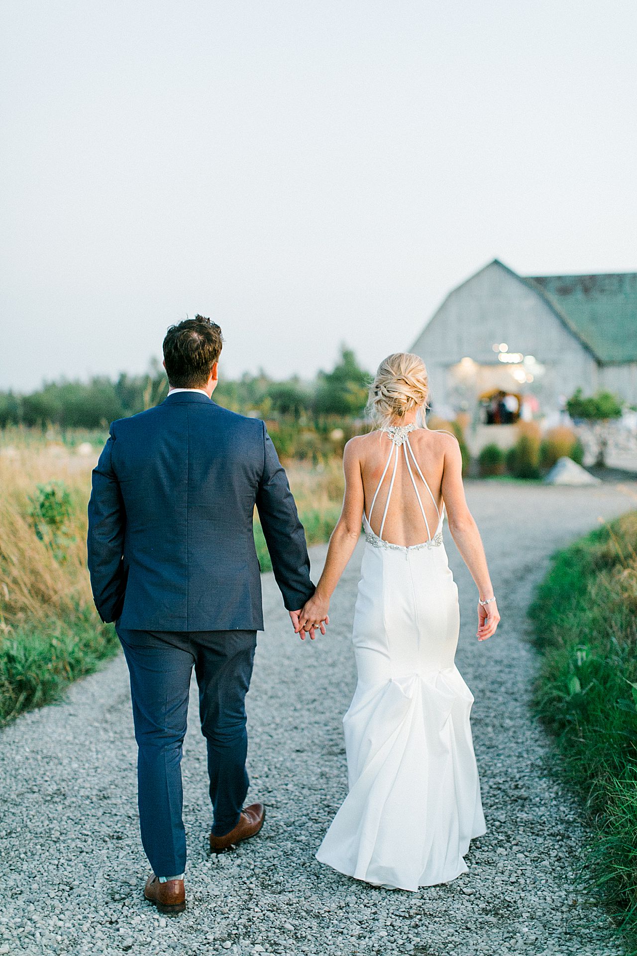 A bride and groom holding hands and walking back to the wedding reception in Northern Michigan
