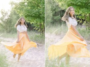 A portrait of a high school senior girl twirling her yellow flowing skirt while walking along a sandy pathway in Charlevoix, Michigan